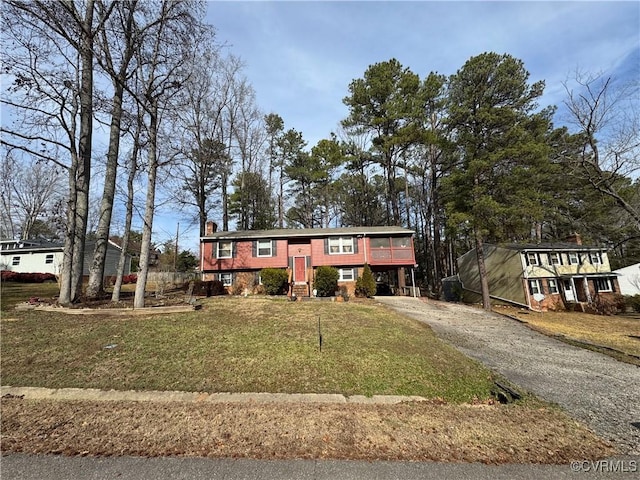 raised ranch with aphalt driveway, a front yard, and a chimney