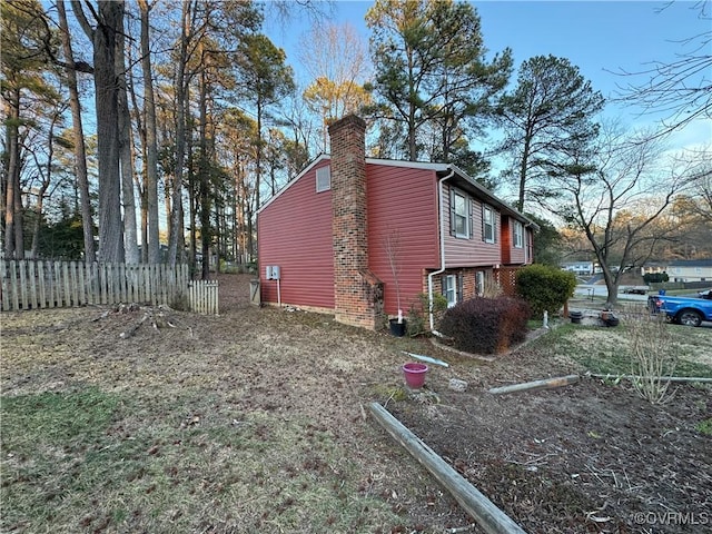 view of property exterior with fence and a chimney