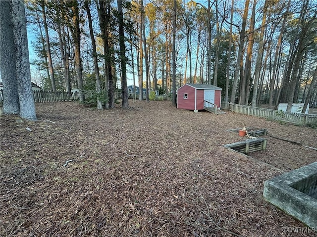 view of yard featuring a storage shed, fence, and an outbuilding