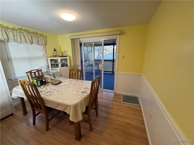 dining space featuring a wainscoted wall, wood finished floors, and visible vents