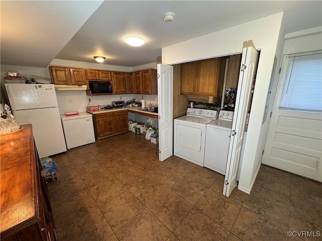 kitchen featuring light countertops, brown cabinetry, freestanding refrigerator, black microwave, and independent washer and dryer