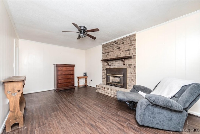 sitting room featuring ceiling fan, dark hardwood / wood-style floors, ornamental molding, a textured ceiling, and a brick fireplace