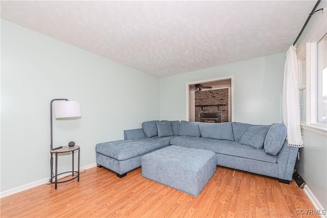 living room with ceiling fan, hardwood / wood-style flooring, a fireplace, and a textured ceiling