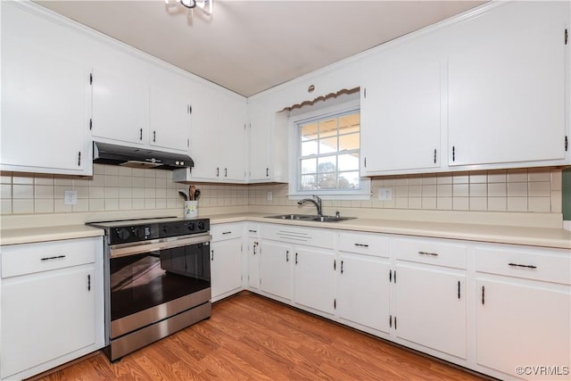 kitchen with electric stove, sink, and white cabinets