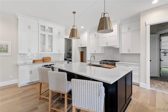 kitchen with white cabinetry, an island with sink, and sink