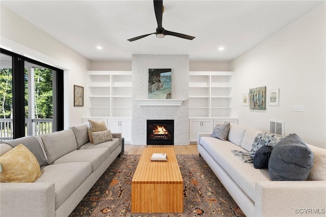 living room featuring ceiling fan, dark hardwood / wood-style flooring, a brick fireplace, and built in features