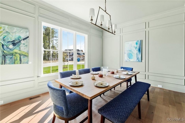 dining area with ornamental molding, hardwood / wood-style floors, and a notable chandelier