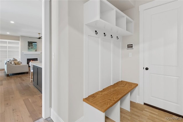 mudroom featuring a brick fireplace and light hardwood / wood-style flooring