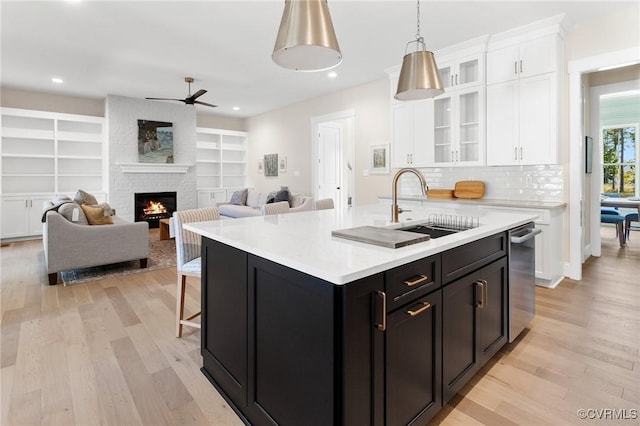 kitchen with white cabinets, sink, a kitchen island with sink, and light hardwood / wood-style floors