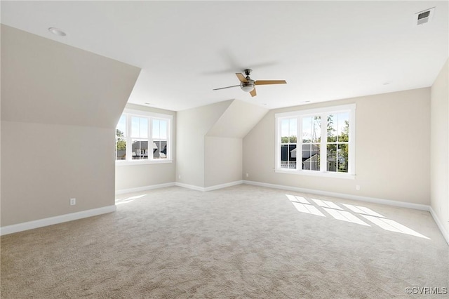 bonus room featuring vaulted ceiling, a healthy amount of sunlight, light carpet, and ceiling fan