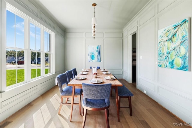 dining room with ornamental molding and light hardwood / wood-style floors