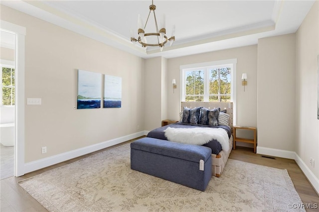 bedroom with a raised ceiling, a chandelier, and multiple windows