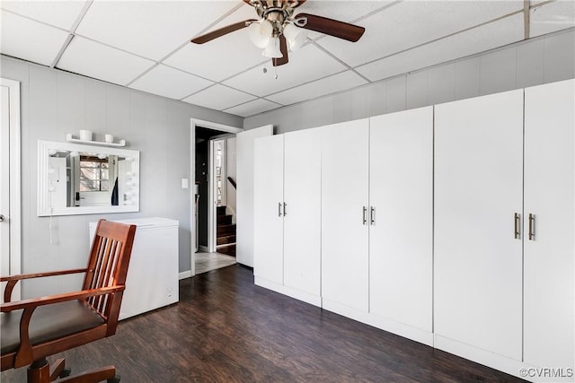 unfurnished room featuring dark wood-type flooring, a drop ceiling, stairway, and a ceiling fan