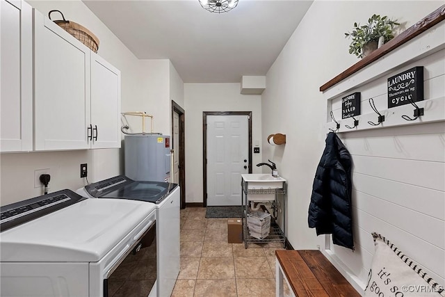 washroom featuring water heater, light tile patterned floors, washing machine and dryer, and cabinets