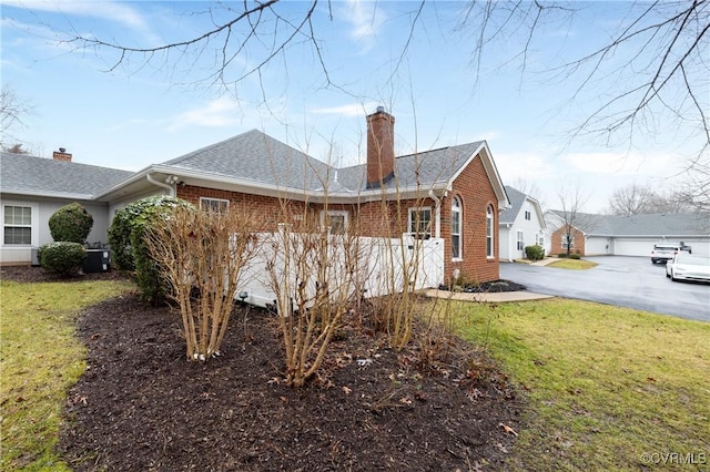 view of home's exterior featuring a garage, a lawn, and central air condition unit