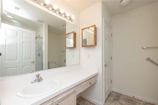 bathroom featuring vanity, toilet, and a shower with door