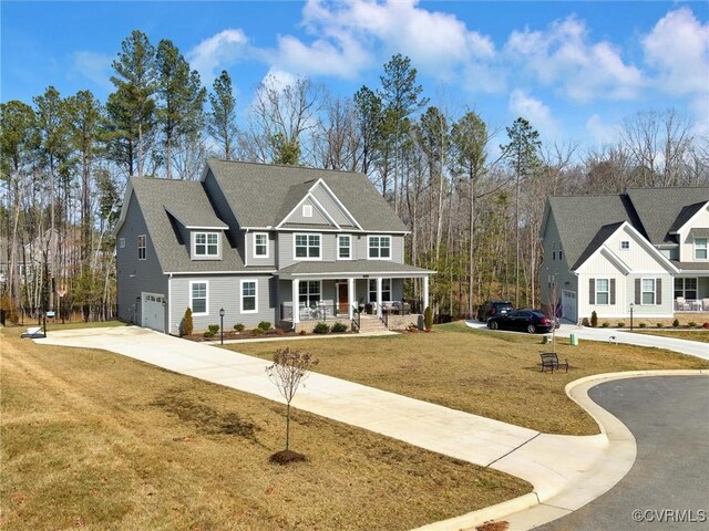 view of front of property featuring a porch, an attached garage, concrete driveway, roof with shingles, and a front yard