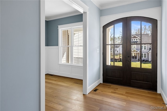 foyer featuring light hardwood / wood-style flooring, ornamental molding, and french doors