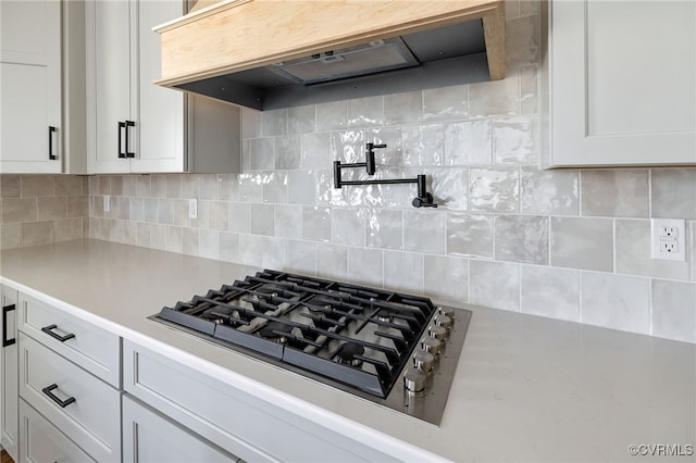 kitchen featuring white cabinetry, gas stovetop, backsplash, and premium range hood