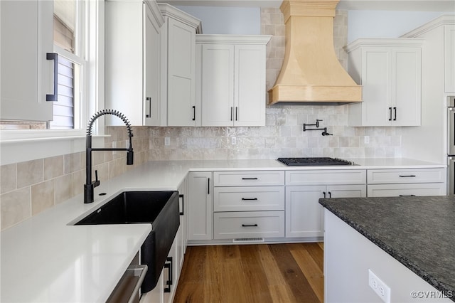 kitchen featuring premium range hood, dark hardwood / wood-style floors, white cabinets, decorative backsplash, and stainless steel gas stovetop