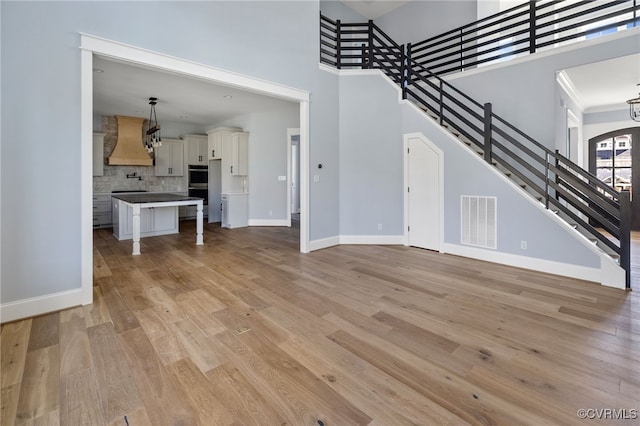 unfurnished living room with light hardwood / wood-style flooring and a high ceiling