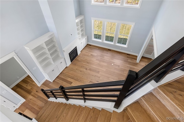 stairway with hardwood / wood-style flooring, a towering ceiling, and built in features