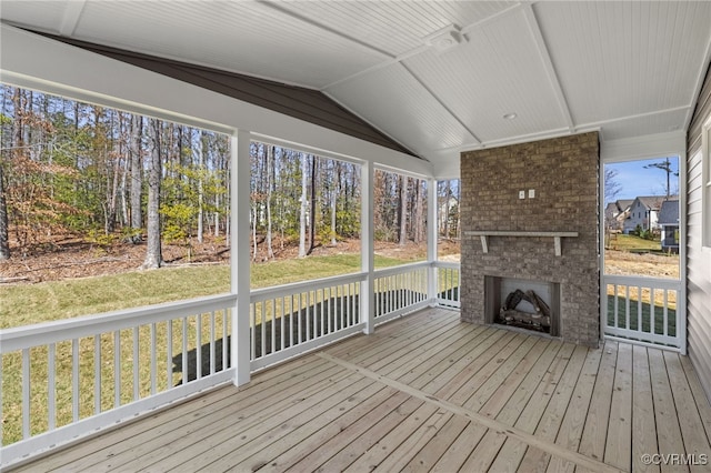 unfurnished sunroom with an outdoor brick fireplace and vaulted ceiling