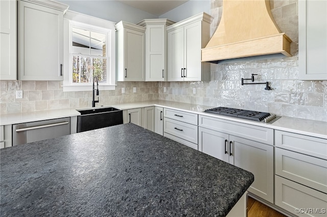 kitchen with sink, backsplash, stainless steel appliances, custom range hood, and dark hardwood / wood-style flooring