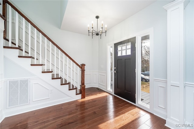 entryway with hardwood / wood-style flooring, visible vents, stairway, and a decorative wall