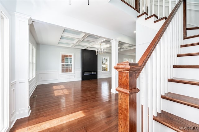 interior space with coffered ceiling, an inviting chandelier, hardwood / wood-style floors, beam ceiling, and decorative columns