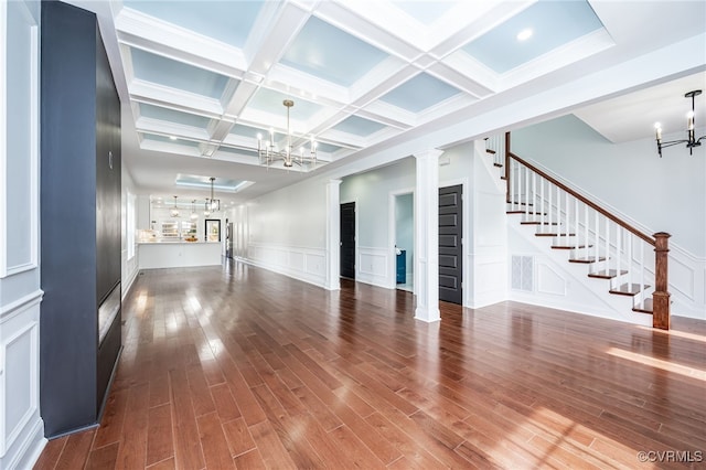 unfurnished living room featuring decorative columns, beamed ceiling, hardwood / wood-style flooring, coffered ceiling, and a notable chandelier