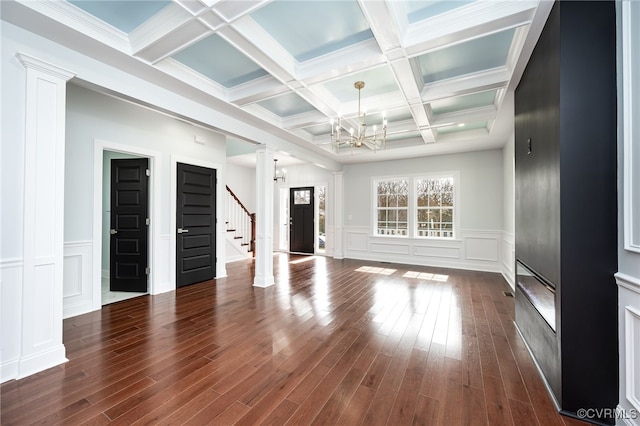 unfurnished living room with beam ceiling, dark hardwood / wood-style flooring, decorative columns, and a notable chandelier