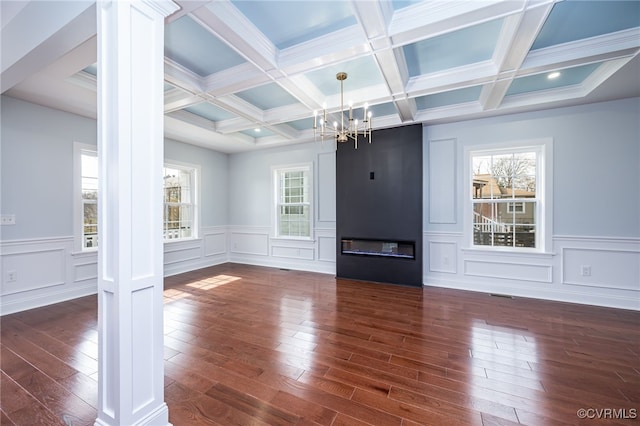 unfurnished living room with plenty of natural light, beamed ceiling, and ornate columns