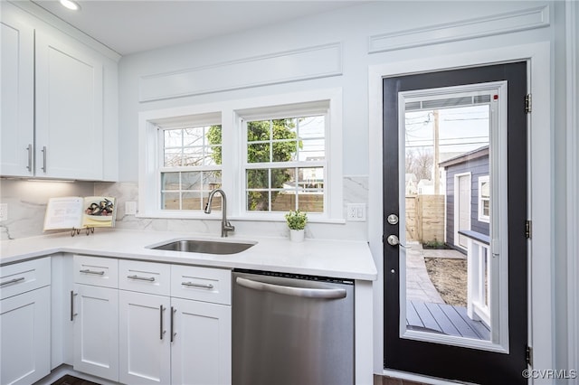 kitchen featuring backsplash, dishwasher, sink, and white cabinets