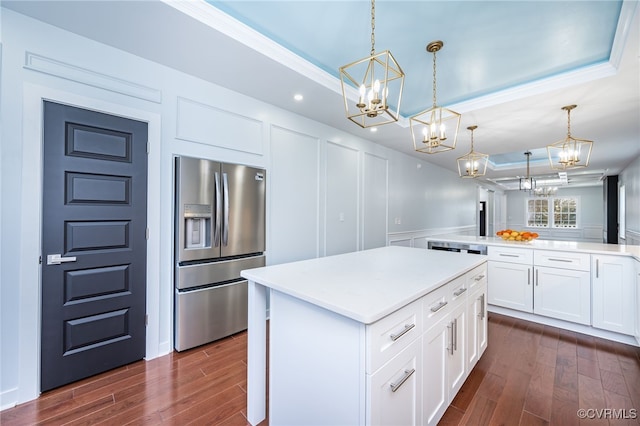 kitchen with a tray ceiling, decorative light fixtures, stainless steel fridge with ice dispenser, and white cabinets