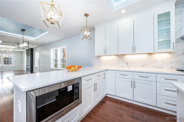 kitchen featuring built in microwave, white cabinetry, dark hardwood / wood-style floors, and decorative light fixtures