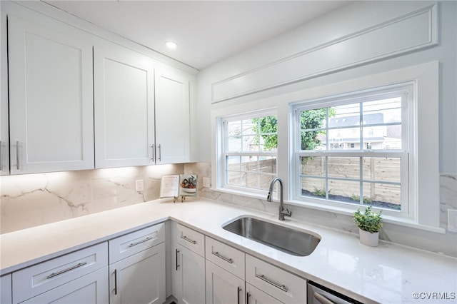 kitchen featuring sink, white cabinets, and backsplash