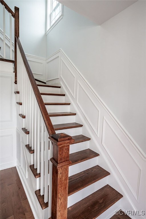 stairway featuring a wainscoted wall, wood finished floors, and a decorative wall