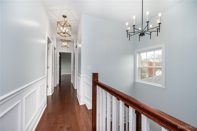 hallway with an inviting chandelier, an upstairs landing, and a wainscoted wall