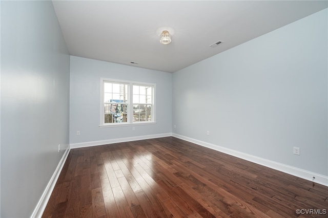 spare room featuring baseboards, dark wood finished floors, and visible vents