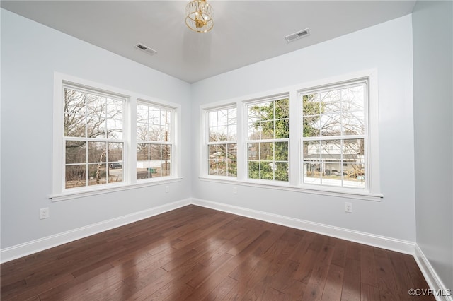 unfurnished room with baseboards, visible vents, and dark wood-style floors