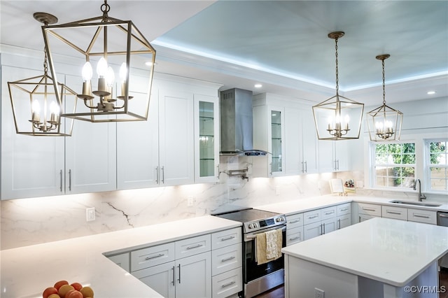 kitchen featuring wall chimney exhaust hood, white cabinets, a chandelier, a sink, and stainless steel electric range oven