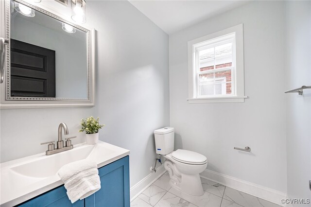 bathroom with toilet, baseboards, marble finish floor, and vanity