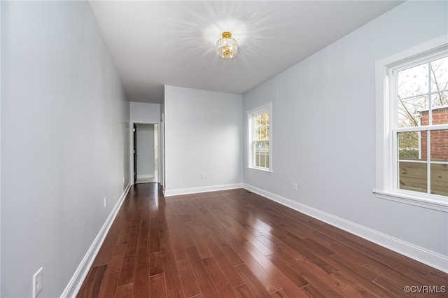 spare room featuring baseboards and dark wood finished floors