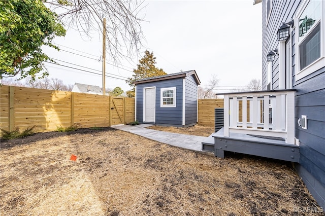view of yard featuring a fenced backyard, a gate, an outdoor structure, and a deck