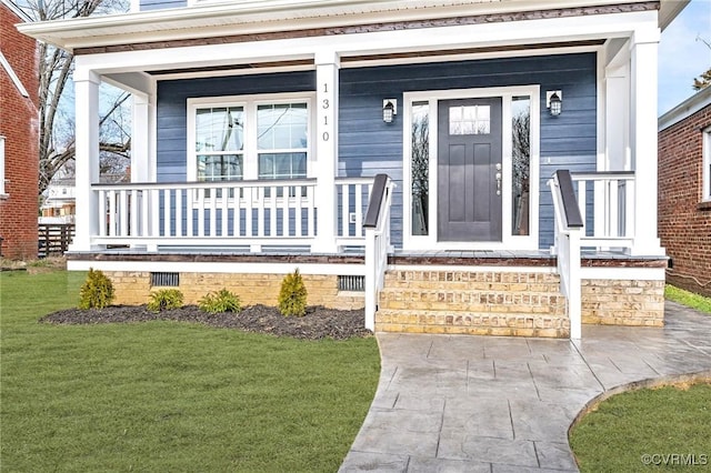 doorway to property featuring a lawn and a porch