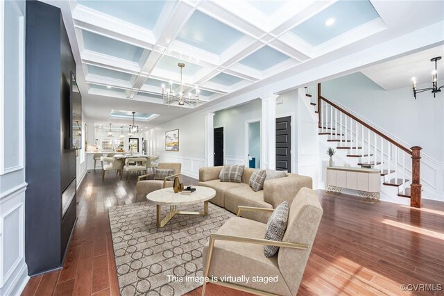 living area with wood-type flooring, a decorative wall, stairs, and a chandelier