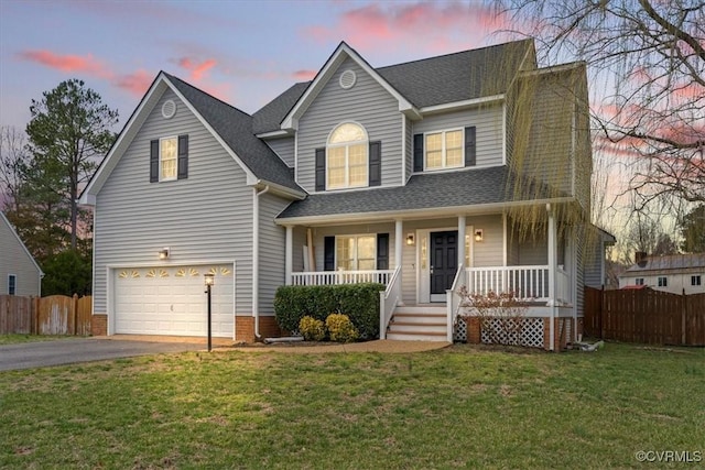 traditional home with a porch, fence, an attached garage, and aphalt driveway