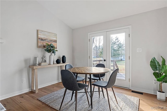 dining space featuring lofted ceiling, french doors, and hardwood / wood-style floors