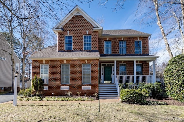 view of front of property featuring brick siding, a porch, and a front yard